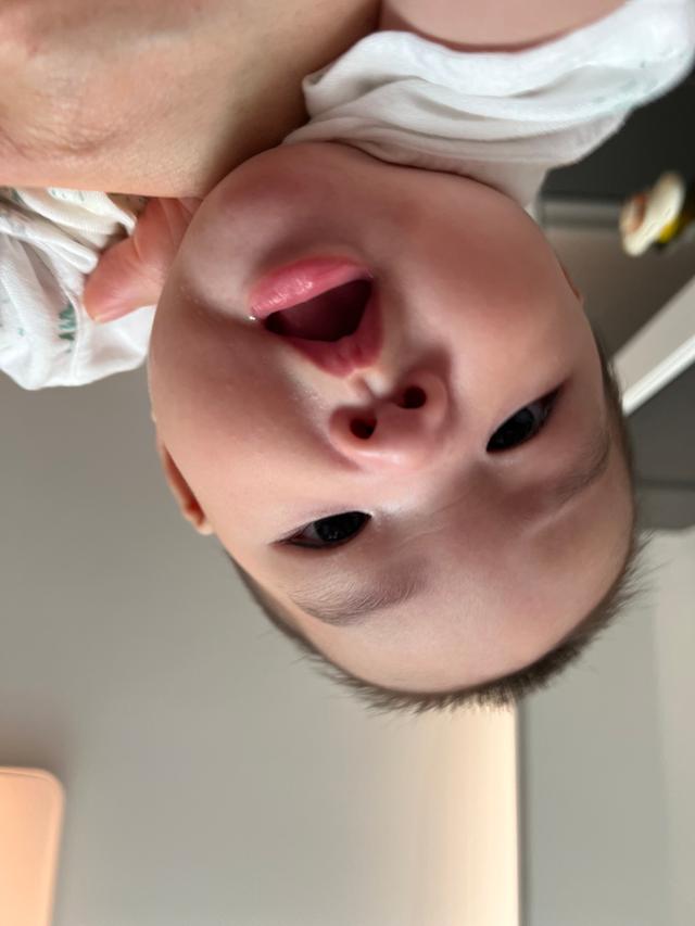 An upside-down close-up of a baby's face, with a focus on the eyes and open mouth